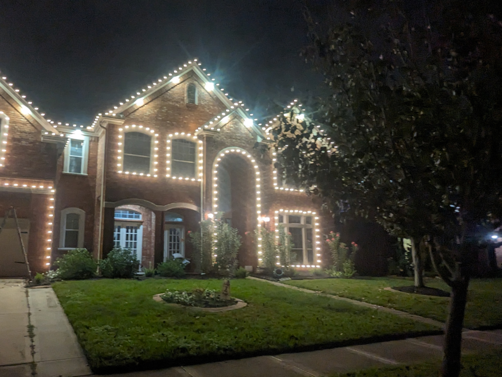 alt="Two-story brick home decorated with white LED Christmas lights by Wayne’s Christmas Lights in Houston."